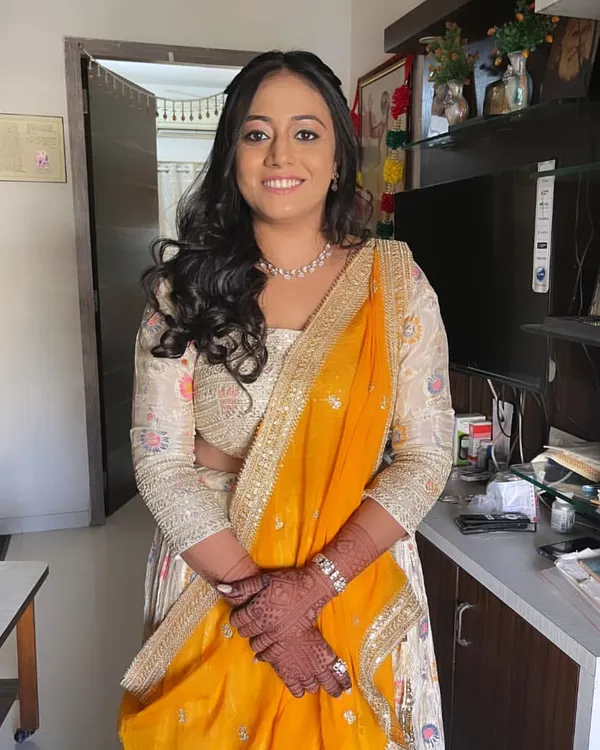 A beautiful client ready for her engagement. Her makeup is soft and glowing, paired with a yellow and white lehenga and loose curls.