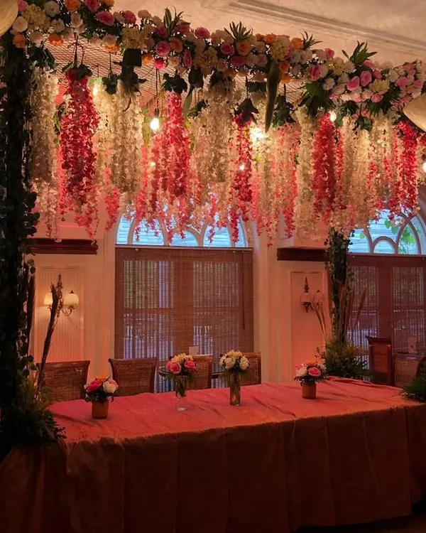 A beautifully decorated head table for a wedding dinner. We created a stunning overhead installation with hanging wisteria and other flowers, creating an intimate and luxurious dining experience.