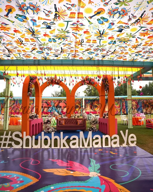 A full view of our fun Carnival-themed Mehendi. The custom printed ceiling and dance floor, colorful arches, and playful hashtag sign create a vibrant and energetic atmosphere.