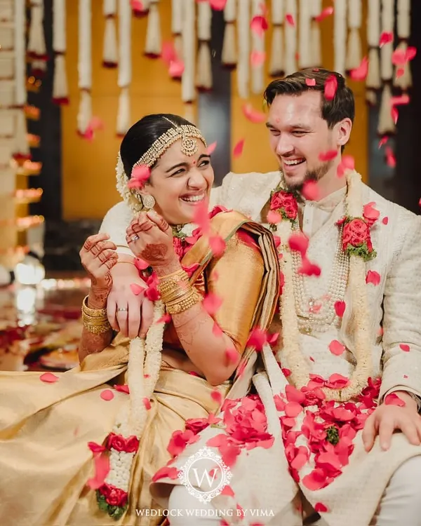 A beautiful moment of love and laughter between the bride and groom, showered with rose petals during their traditional wedding ceremony. These are the moments we live for.