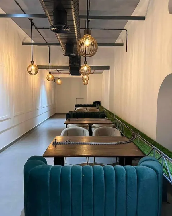 The interior of Kritunga Restaurant, a commercial project we designed. This view shows the linear seating arrangement with plush teal banquettes and a unique conveyor belt system for serving food, creating a memorable dining experience.