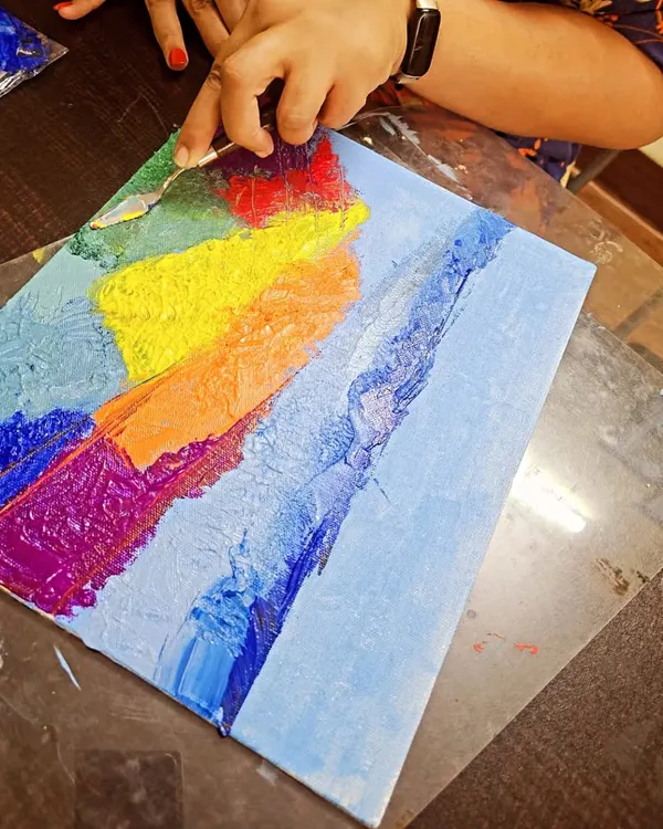 A participant works on her abstract landscape using a palette knife. This technique is perfect for creating rich textures and expressive strokes.