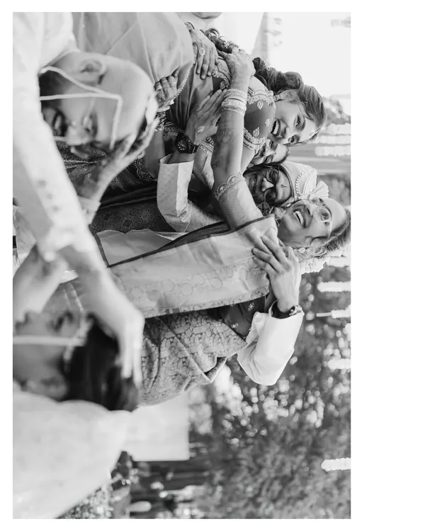 A candid, joyful moment from Mohita and Tejas's wedding. The black and white format emphasizes the raw emotion and laughter being shared among family and friends.