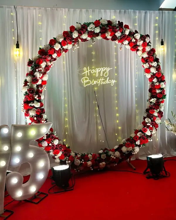 A grand celebration for a 75th birthday, featuring large illuminated marquee numbers and a classic red and white floral ring. The red carpet and spotlights create a VIP experience for the guest of honor.