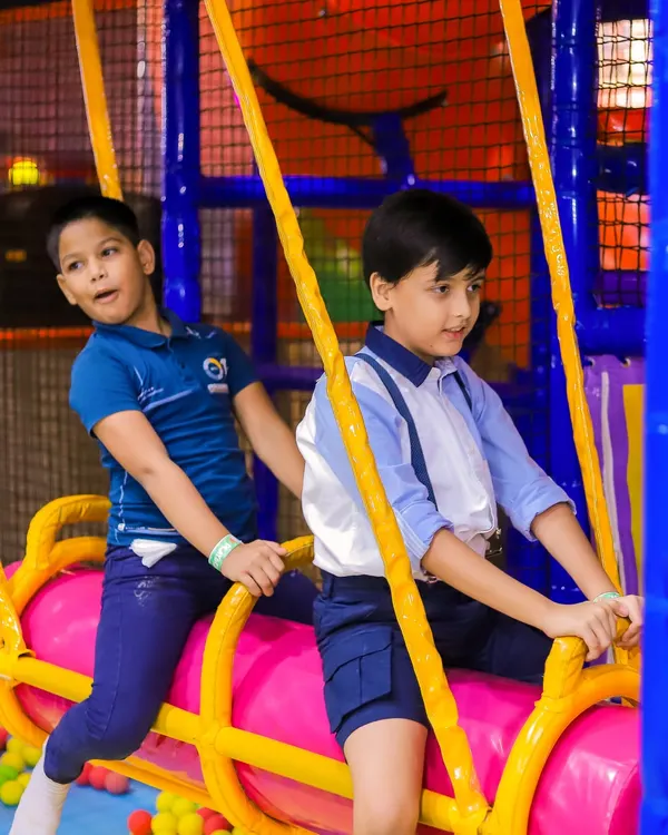 Two boys work together on the swinging log over the ball pit, a fun challenge in our play maze.