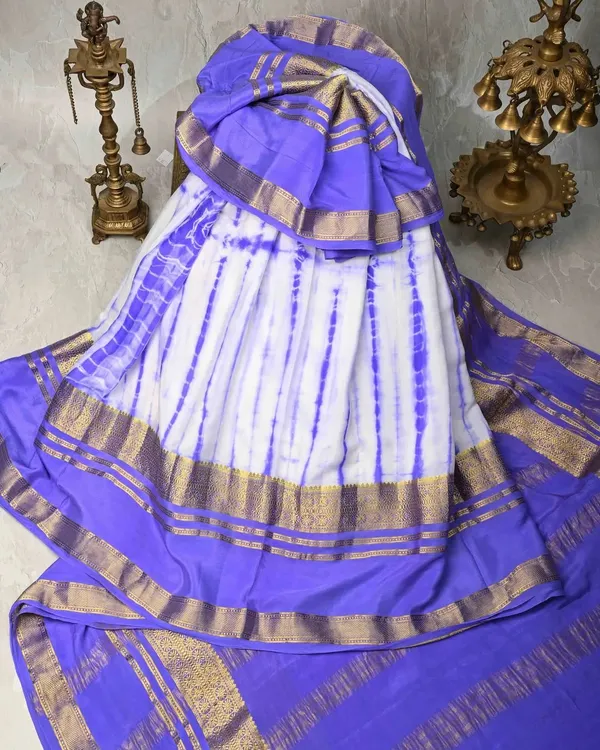 A unique tie-dye silk saree in white and purple with a classic gold border. This is a modern twist on a traditional fabric, perfect for making a style statement.
