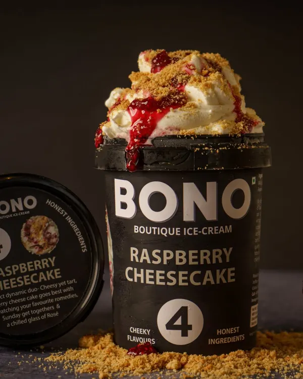 A perfect scoop shot for Bono Boutique Ice Cream. The styling with crumbled biscuits and raspberry sauce highlights the 'Raspberry Cheesecake' flavor and makes the product look indulgent and ready to eat. This is ideal for social media and product listings.