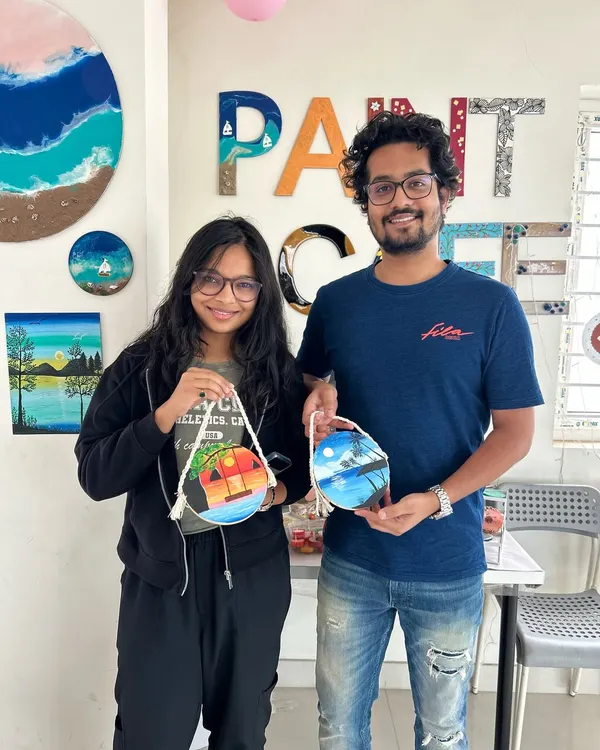 A happy couple showing off the beautiful paintings they created on wooden discs.