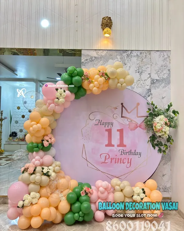An elegant 11th birthday for Princy with a pastel theme. The round backdrop is framed by a delicate balloon arch in peach, green, and cream, with floral accents.