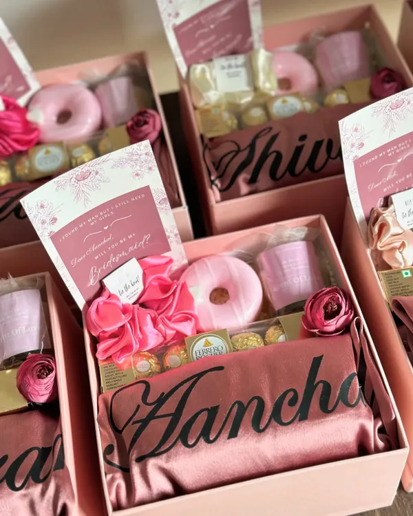 We believe your bridesmaids deserve the best! This proposal hamper is packed with love, including a personalized satin robe, a donut-shaped soap, a scented candle, and delicious Ferrero Rocher chocolates, all presented in a beautiful pink box.