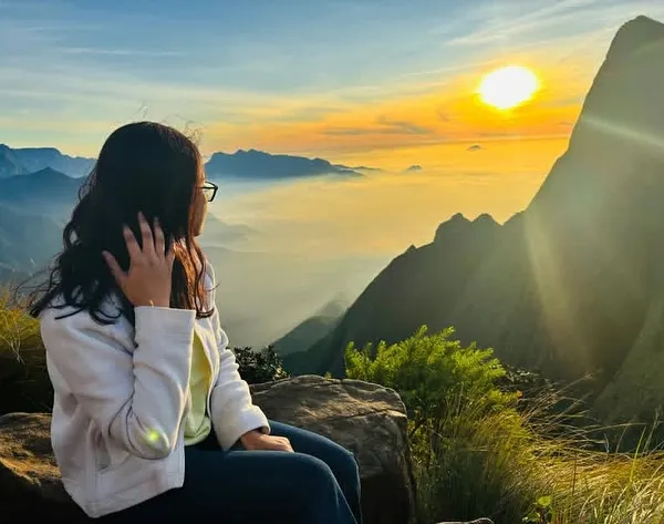 A traveler watching the sun rise over a sea of clouds at Kolukkumalai. This is a core memory from our Munnar trip.