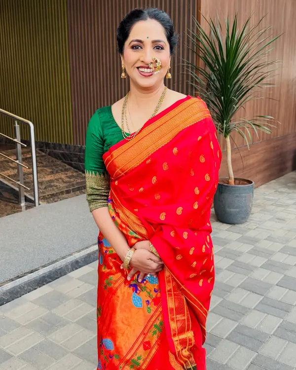 A full-length portrait of actress Madhurani Prabhulkar in a vibrant red saree.