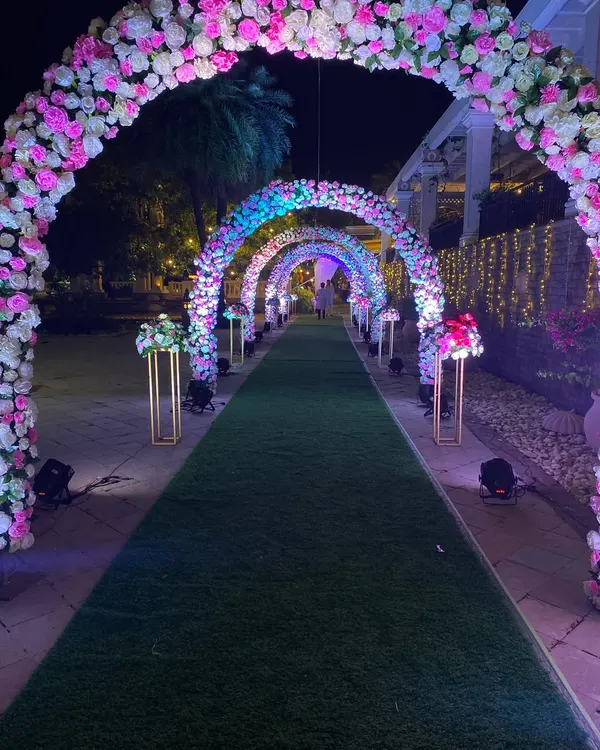 The same floral archway from the daytime, now transformed for the evening reception. We used strategic uplighting to make the pink and white flowers pop against the night sky, creating a completely different, glamorous mood.