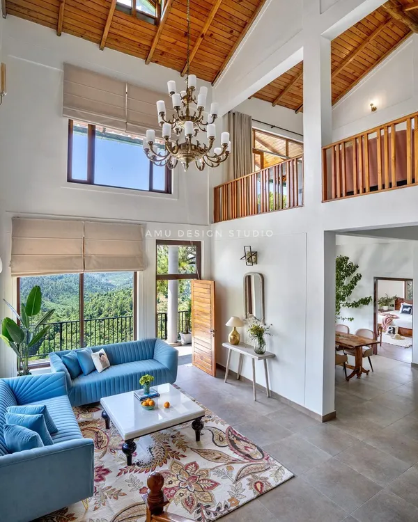 We designed this double-height living room in a Mukteshwar holiday home to be a grand yet inviting space. The towering windows frame the majestic mountain views, while the classic chandelier adds a touch of timeless elegance, creating a perfect sanctuary away from the city.