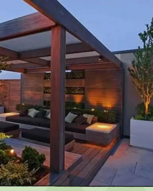 This modern pergola demonstrates how to create a cozy and stylish outdoor living room. The structure provides partial shade and a frame for lighting, while the integrated seating and planters make the space both comfortable and green.