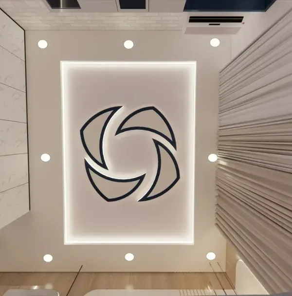 A worm's-eye view of a creative false ceiling design with a unique geometric cutout and backlighting.