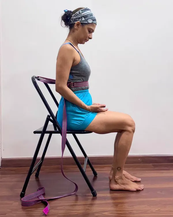 Using a belt around the lower ribs while seated on a chair for pranayama preparation. This simple adjustment prevents the ribs from hardening, allowing the diaphragm to relax and creating the correct internal state for breathwork.