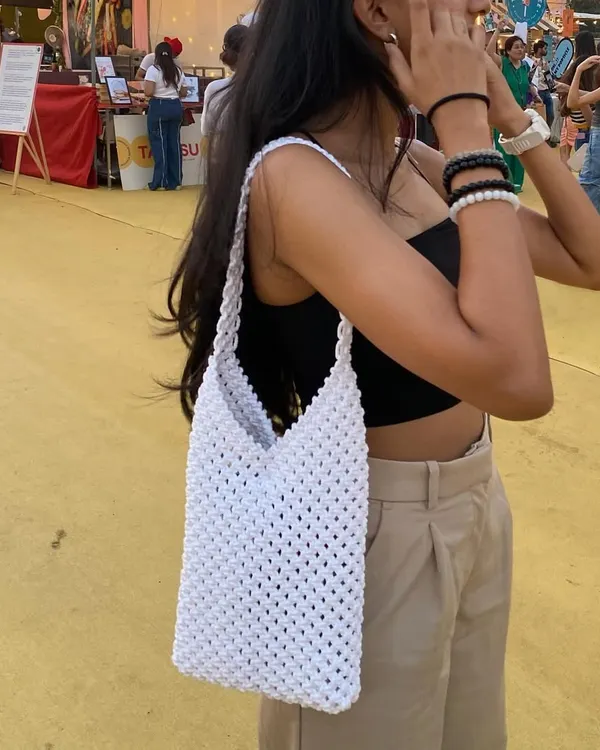 This is our classic white macrame shoulder bag, pictured at a local flea market. Its simple, open-knot design is lightweight and perfect for a sunny day out.