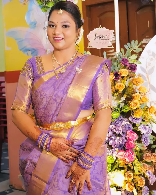 A gorgeous bride-to-be for her engagement ceremony. She looks radiant in her purple Kanjeevaram saree, with makeup that is both traditional and glamorous.
