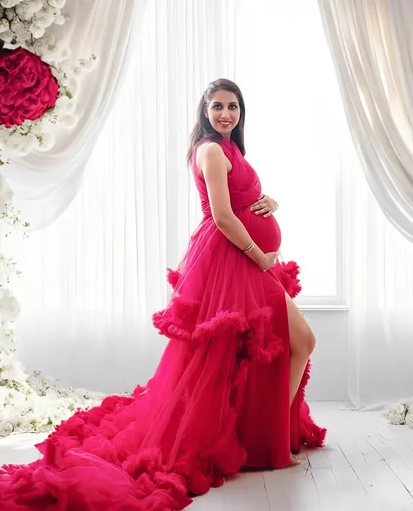 A truly showstopping look. This vibrant ruffled gown paired with a floor-to-ceiling floral arch creates a glamorous and unforgettable maternity portrait.