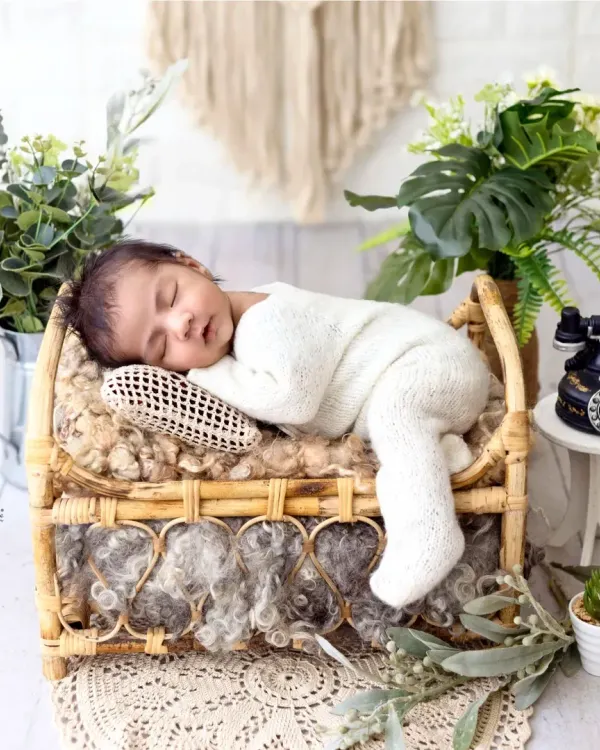 This little one looks so peaceful sleeping on a miniature cane bed. I use natural textures and a soft, neutral color palette to create a calm and timeless newborn portrait.