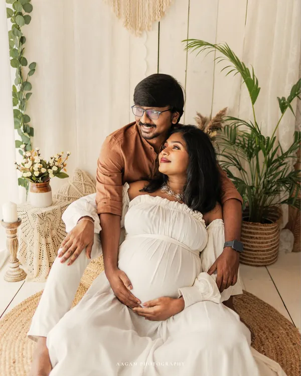 A perfect example of a boho-inspired maternity session. The couple relaxes on a jute rug, surrounded by plants and natural textures, creating a warm and earthy vibe.