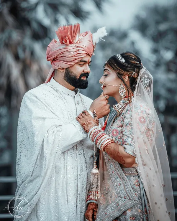 A tender moment between the bride and groom on their wedding day. The groom gently holds his bride's chin, their gazes locked in a portrait that is both intimate and beautifully composed.
