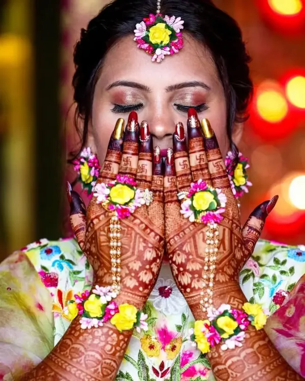 This is my favorite kind of Haldi look. The combination of deep henna stain and delicate floral jewelry on the hands creates a stunning visual for any pre-wedding event.