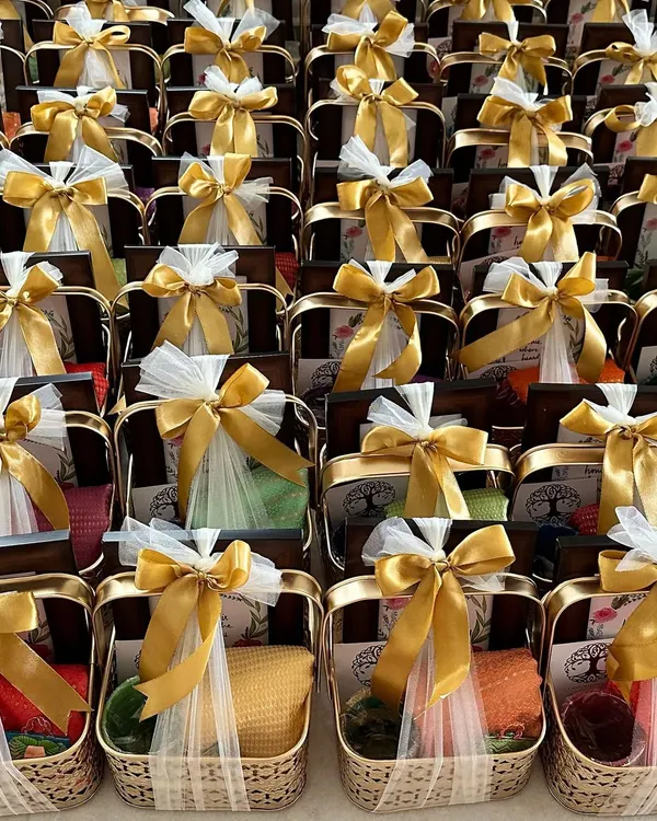 Thoughtful housewarming return favours in elegant golden metal baskets. Each basket contains a blouse piece, glass bangles, a photo frame, and other traditional items to thank guests for their blessings.
