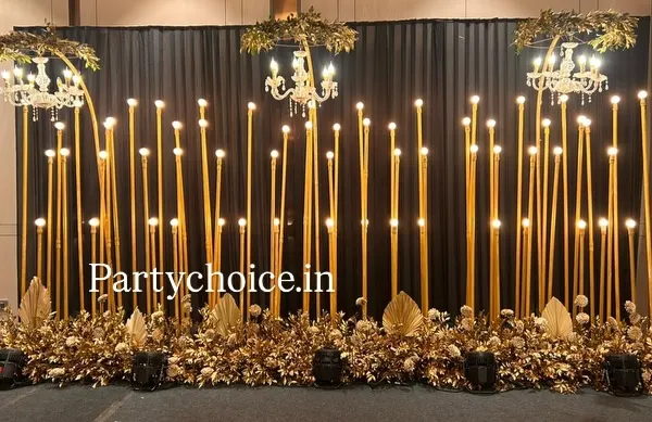 This is a full view of our popular gold and black sangeet stage. The design uses tall, illuminated pillars and elegant chandeliers against a dark backdrop to create a look of pure glamour and sophistication.