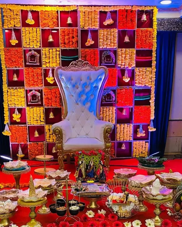 This is a complete Seemantha (baby shower) stage I designed. It features an ornate high-back chair against a custom backdrop made of fresh marigold flowers arranged in a colorful grid pattern, a specialty of mine for traditional functions.