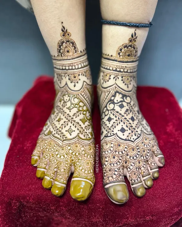 A stunning full-coverage bridal foot mehendi. This design features intricate net patterns, leafy vines, and delicate bands around the ankles, ensuring your feet look beautiful from every angle.