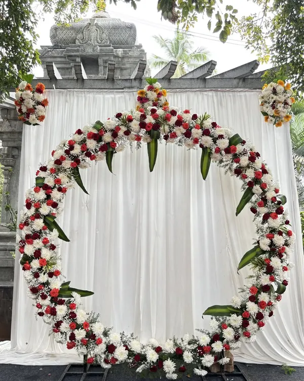 A stunning circular floral arch, perfect for a modern wedding ceremony or reception backdrop. We used a mix of fresh red and white flowers with natural green accents to create this beautiful photo point for an outdoor event.