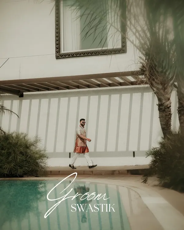 A stylish shot of the groom walking by the poolside. This captures his cool, relaxed demeanor and fashionable attire, a perfect portrait for a destination wedding.