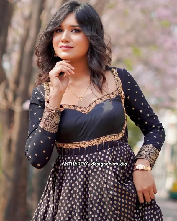 A close-up of a black and gold Anarkali-style gown, featuring a sweetheart neckline and intricate border work.