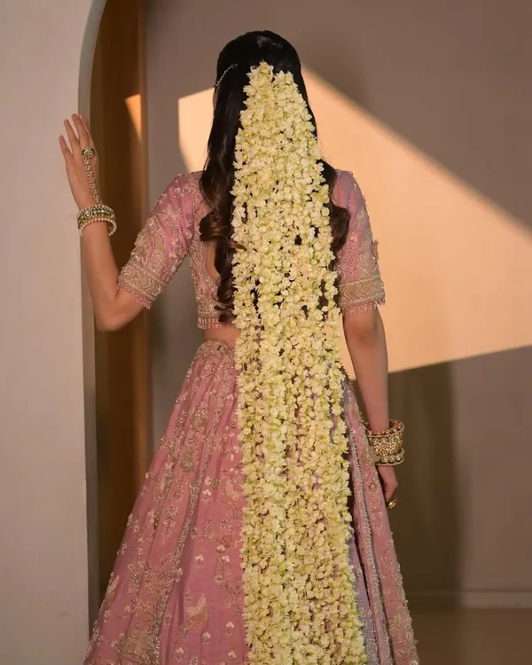 This dramatic cascade of fresh jasmine flowers, known as a mogra veil, creates a truly unforgettable bridal statement. I designed this half-up hairstyle with soft waves to balance the grandeur of the flowers, perfect for a bride who wants a blend of tradition and modern fantasy.