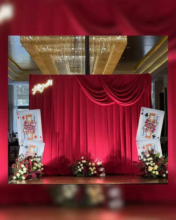 A grand reveal for a 75th birthday bash. The stage is set with dramatic red velvet curtains and oversized "King" playing cards, promising a night of royal casino fun.