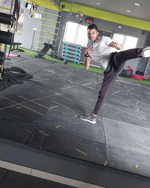 A dynamic side kick captured in the mirror. This is one of the fundamental moves we practice in cardio kickboxing, focusing on power, balance, and control for a full-body workout.