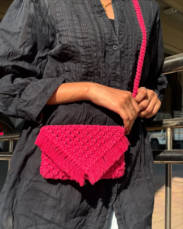 This bright pink macrame sling bag is all about the details. The intricate knotting and fringed envelope flap give it a boho-chic feel, making it a standout accessory.