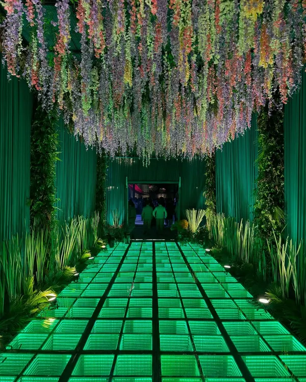 I believe the first step into your celebration should be a step into another world. This immersive entrance uses a custom-built infinity mirror walkway, lush green draping, and a ceiling of cascading wisteria to create a dramatic, unforgettable welcome for a modern cocktail event.