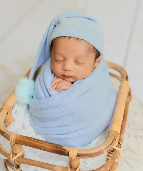 Snuggled up and dreaming in soft blue hues. This classic basket pose with a sleepy hat is a timeless way to capture the sweetness of a newborn boy.