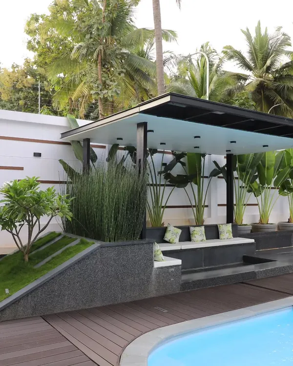 A modern poolside gazebo I designed and built, featuring a sunken seating area. The structure is integrated with planters containing tall grasses and a small tree on a berm, blending architecture with the landscape.