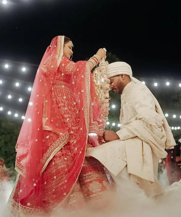 A magical Varmala moment, as the bride places the garland on the groom under a sky of string lights and surrounded by ethereal smoke.