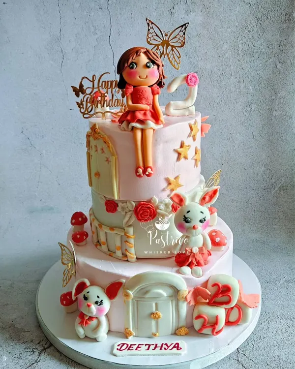 This two-tiered cake was a dream to make for a second birthday, featuring a hand-modelled fondant doll, adorable bunnies, and delicate butterfly accents.