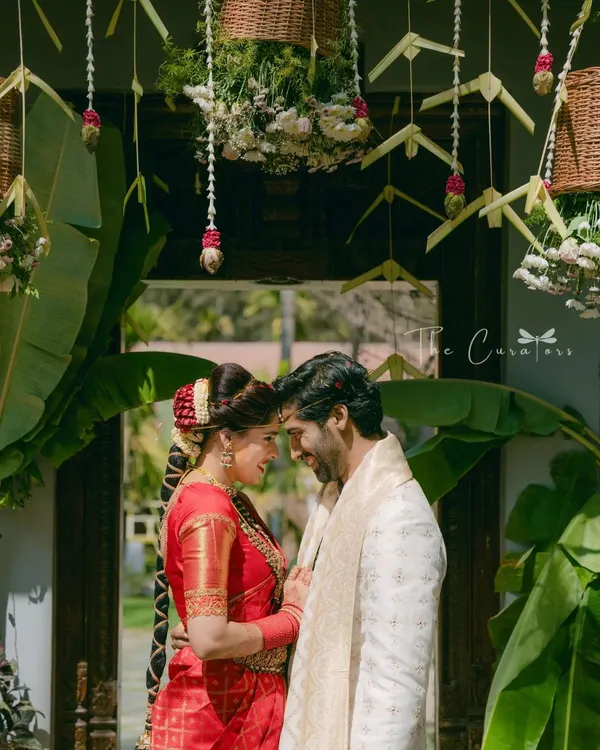 A moment of quiet connection between the couple, framed by a traditionally decorated doorway. We used banana leaves and hanging floral baskets to honor South Indian wedding customs.