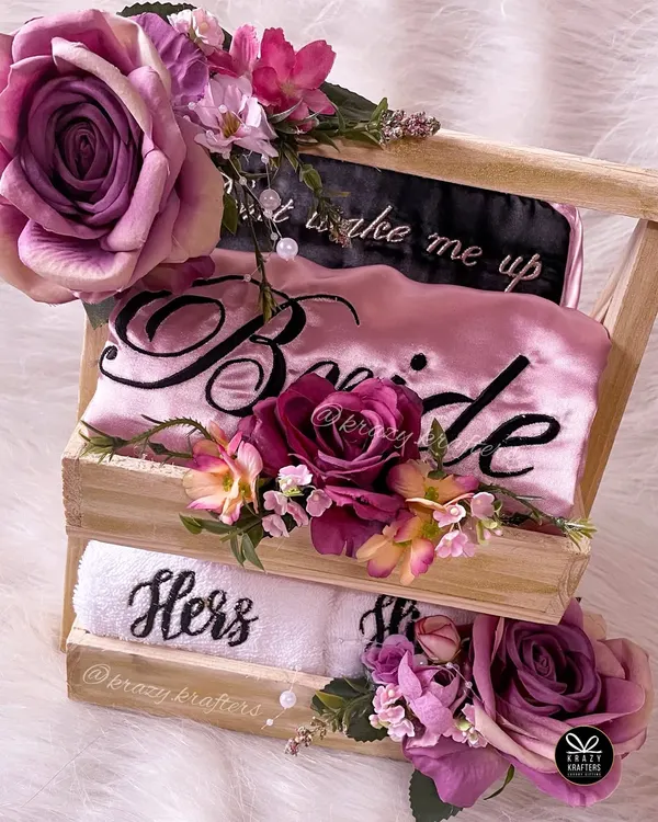 A bride hamper in all its glory. This wooden crate is styled with beautiful purple flowers and contains a personalized 'Bride' robe and 'Hers' towel for a touch of luxury.