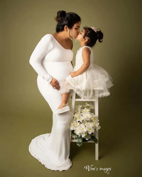 A mother's love is a bond like no other. This tender moment, a sweet kiss from her firstborn, perfectly captures the love that is about to expand to welcome a new family member.
