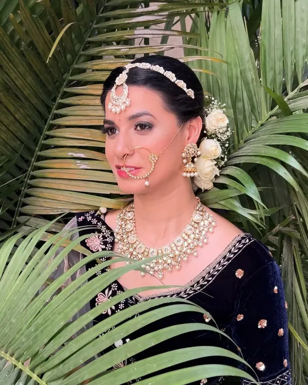 An editorial-style shoot featuring a regal look with a dark velvet blouse, kundan jewelry, and a classic floral bun.