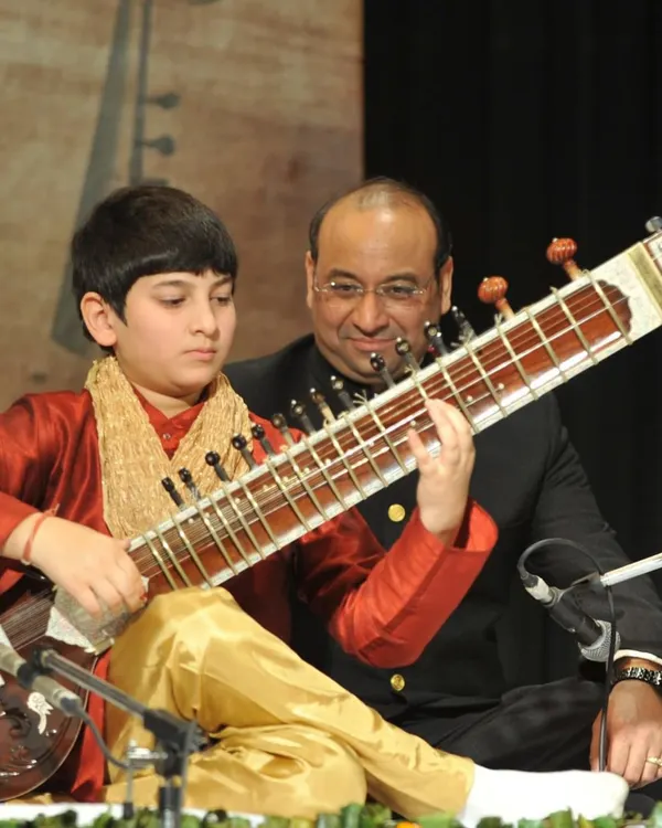 A photo of my father and first guru, Sanjay Rikhiram, introducing me on stage for the first time. My musical journey is rooted in my family's century-long tradition of handcrafting the finest Indian instruments.