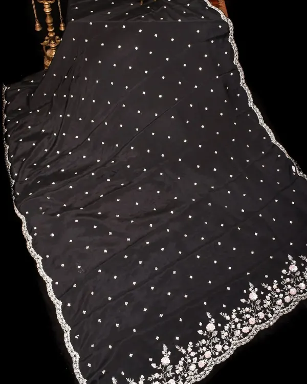 A stunning black georgette saree with delicate white polka dots and an exquisitely embroidered floral border in silver. This is a timeless piece for any elegant evening affair.